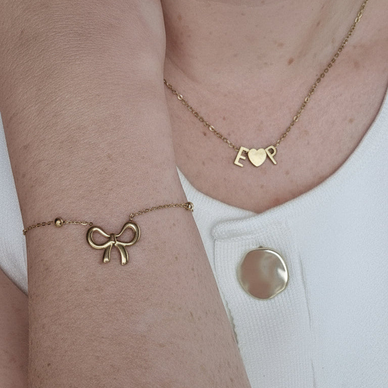 Close-up of a person's wrist wearing gold bracelets with a white garment in the background.