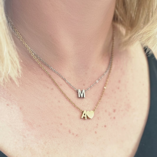 Close-up of a person wearing a delicate gold necklace with heart pendant.