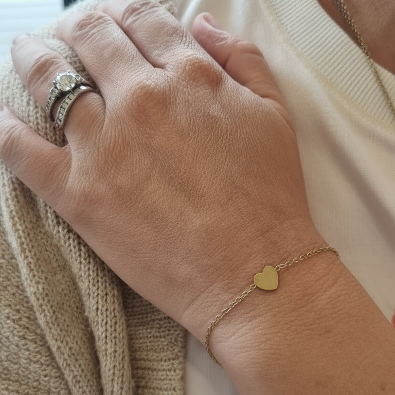 Close-up of a person's hands with jewelry, wearing a beige garment with red text.