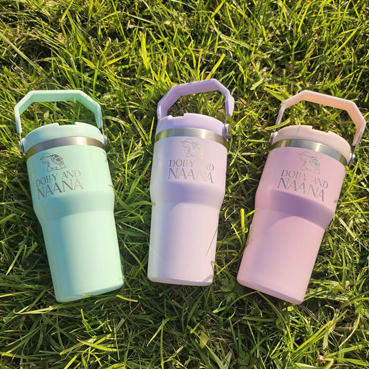 Three colorful tumblers with handles on a grassy background