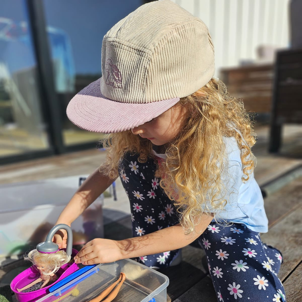 Child playing with dolls and toys on a wooden deck